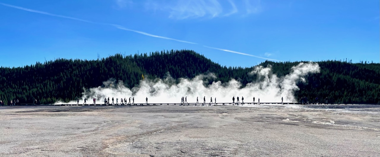 silhouetten lopen voor Grand Prismatic Spring langs